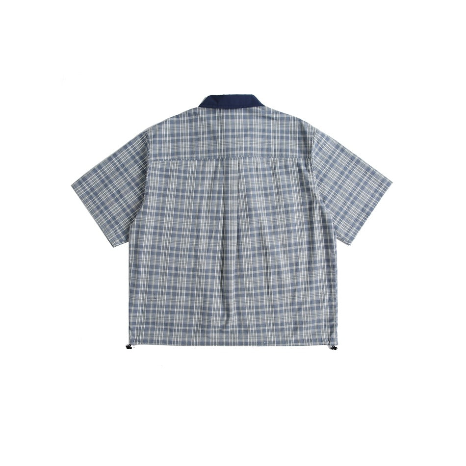 Back view of a blue-gray plaid short-sleeve shirt with a navy collar and center pleat.