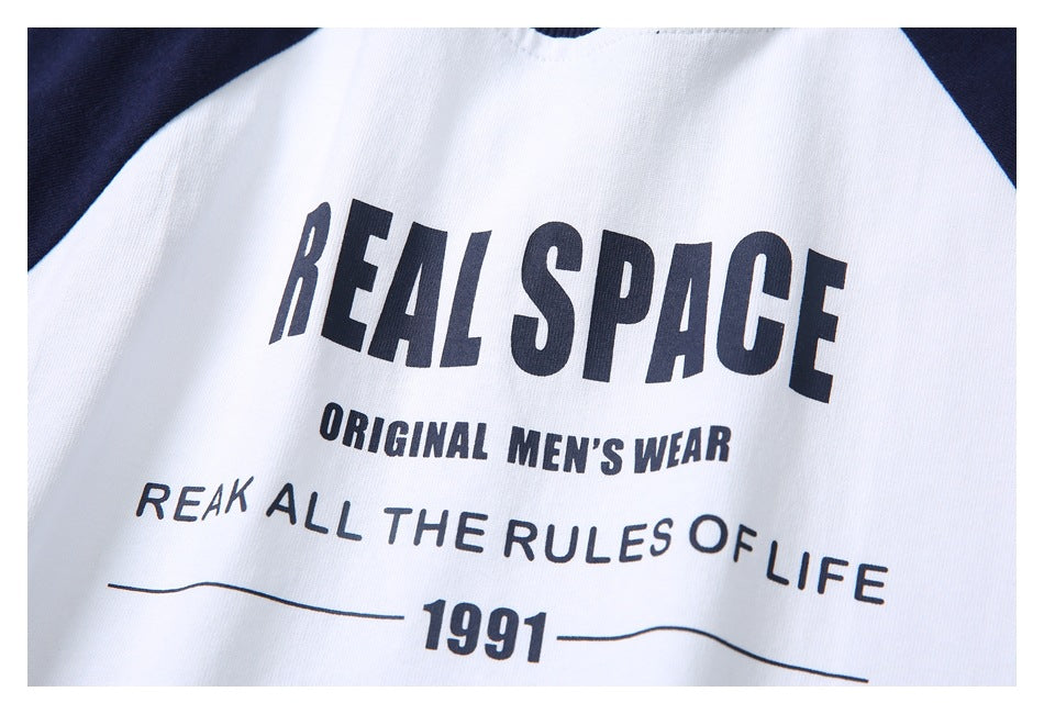 Close-up of a white shirt with navy raglan sleeves and a printed dark text graphic.