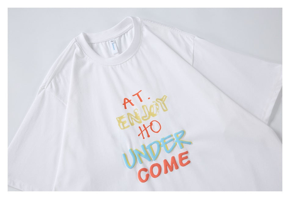 Close-up of a white crew-neck T-shirt with colorful lettering across the chest.