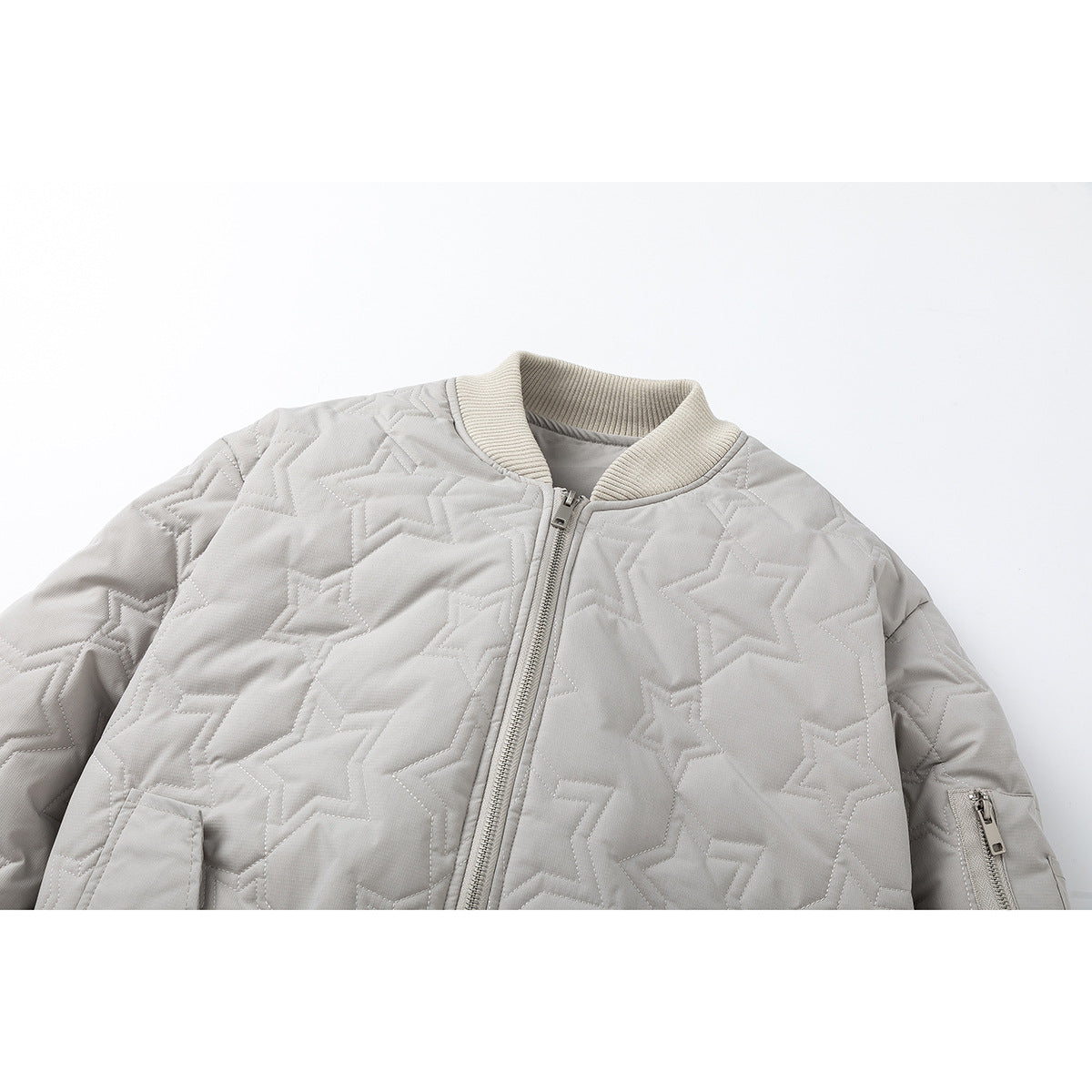 Cropped front view of a light gray quilted jacket with stitched star patterns, a ribbed collar, front zipper, and sleeve