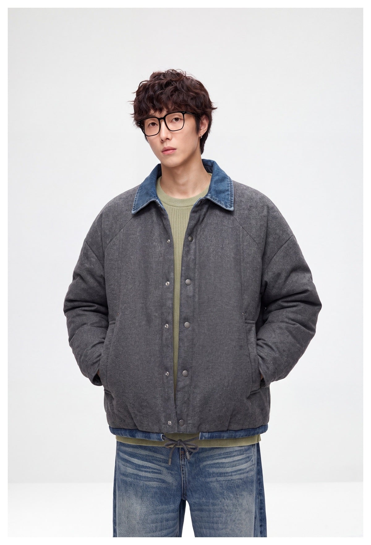 Front view of a model wearing a charcoal-gray snap-front jacket with a blue denim collar and drawcord hem.