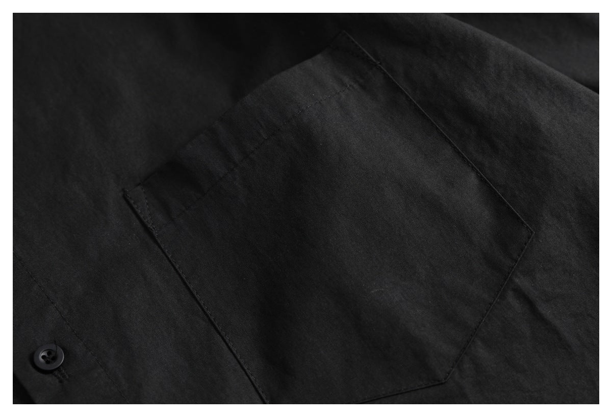 Close-up of a large patch pocket on a black shirt, with a button visible beside it.