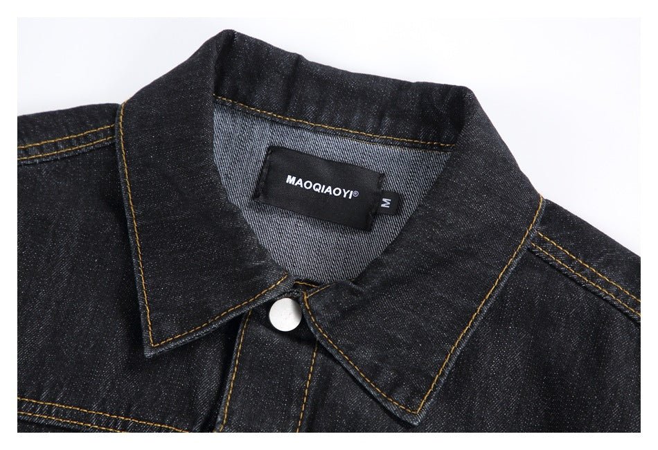 Close-up of the black denim jacket collar, silver snap, and sewn neck label.