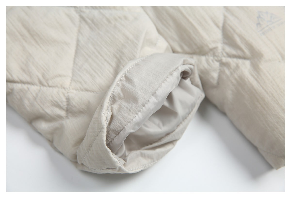 Close-up of the cream jacket's sleeve opening, showing its smooth inner lining and quilted outer fabric.