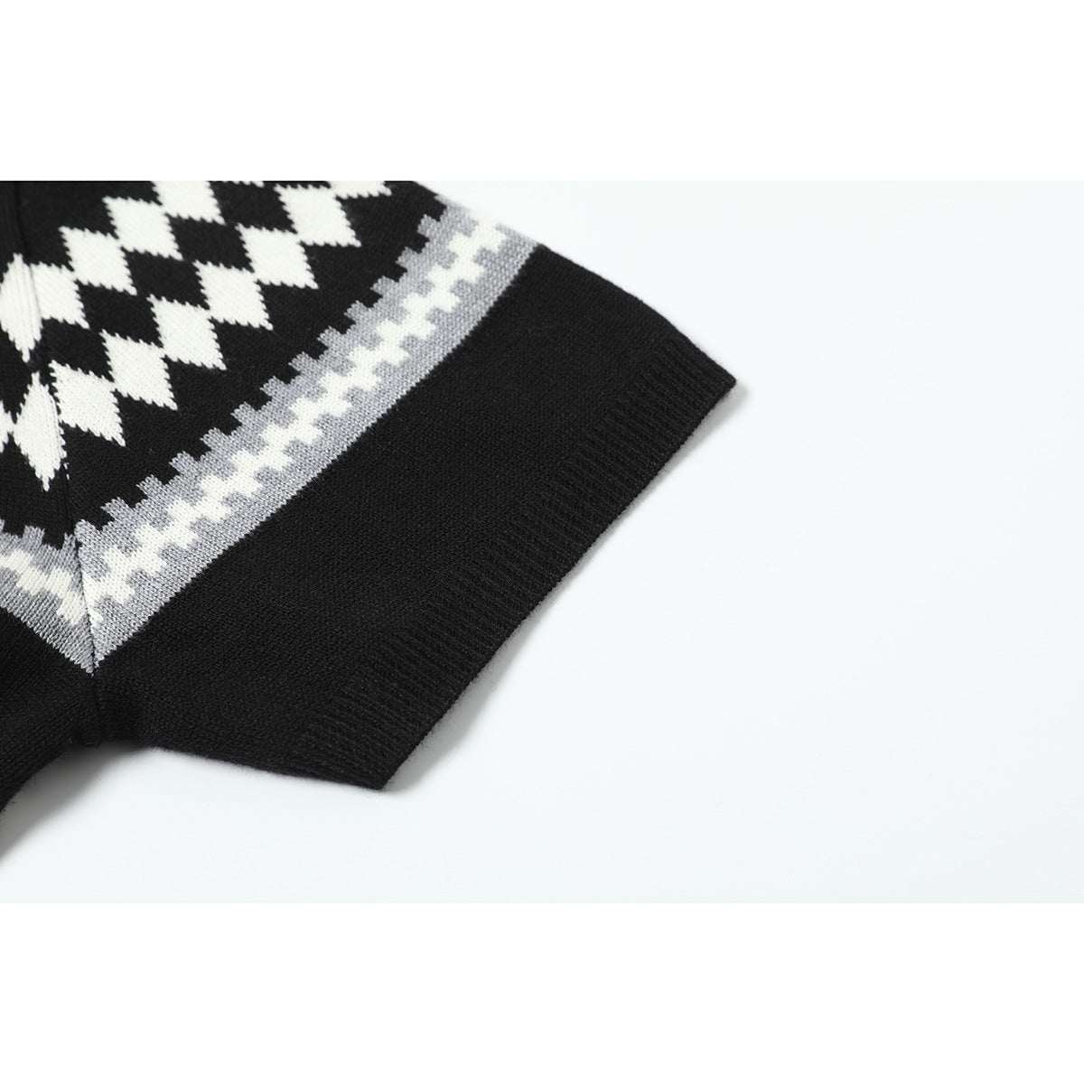 Close-up of the black knit shirt's short sleeve, ribbed cuff, and white and gray geometric stripe.