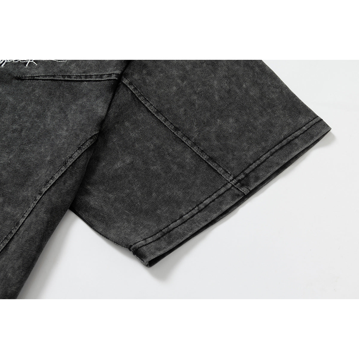 Close-up of a black acid-wash T-shirt sleeve, showing its seam and double-stitched hem.