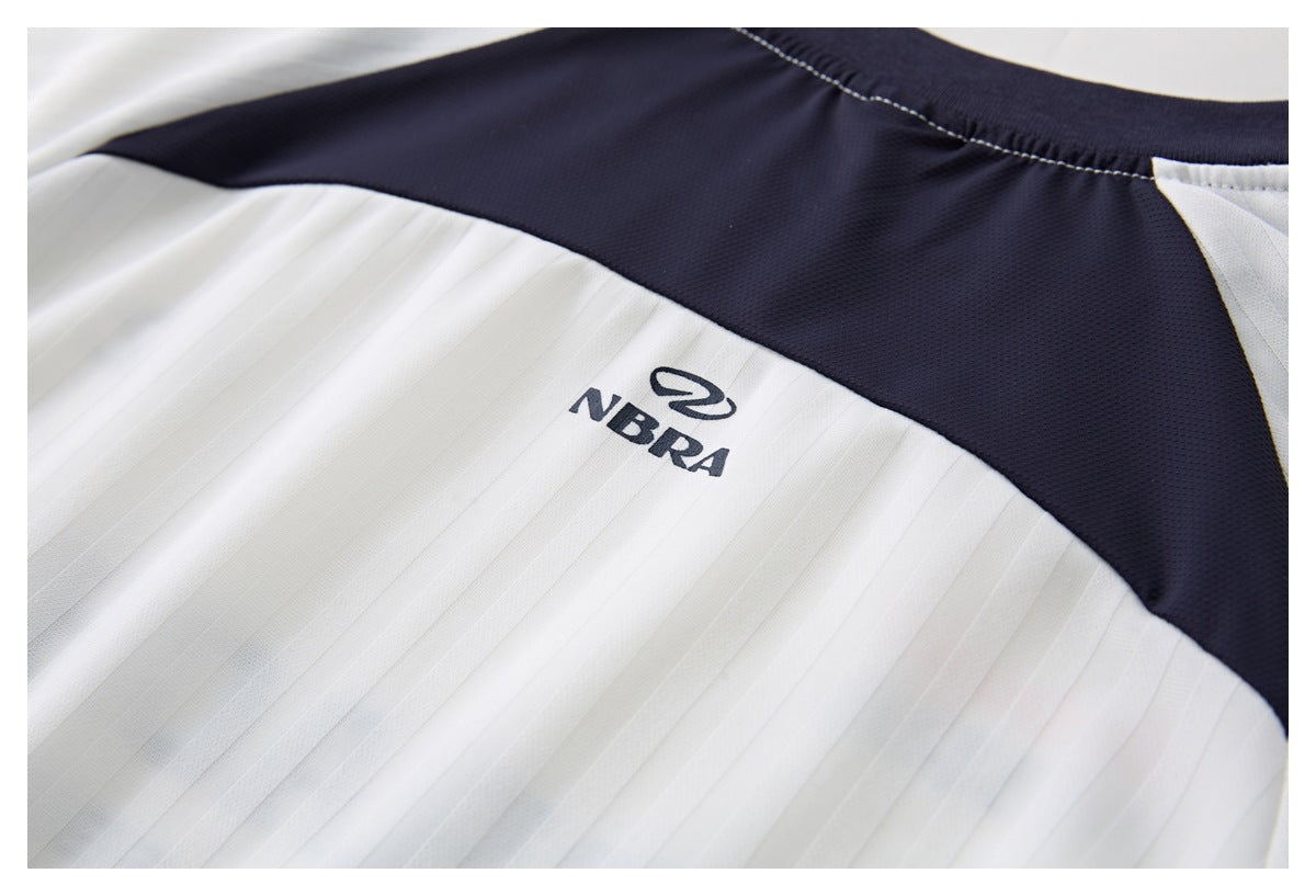 Close-up of a small navy logo on the white pinstriped jersey below a broad navy shoulder panel.
