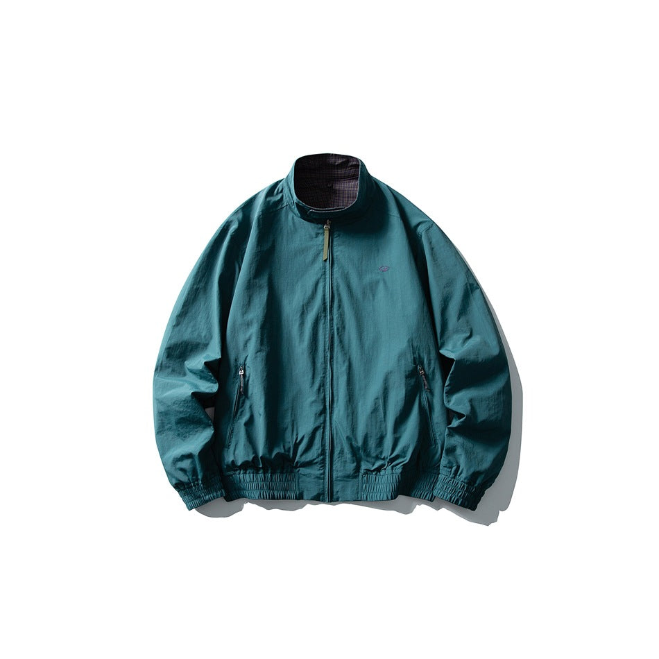 Front view of a teal jacket with a stand collar, front zipper, two zip pockets, and elasticated trim.