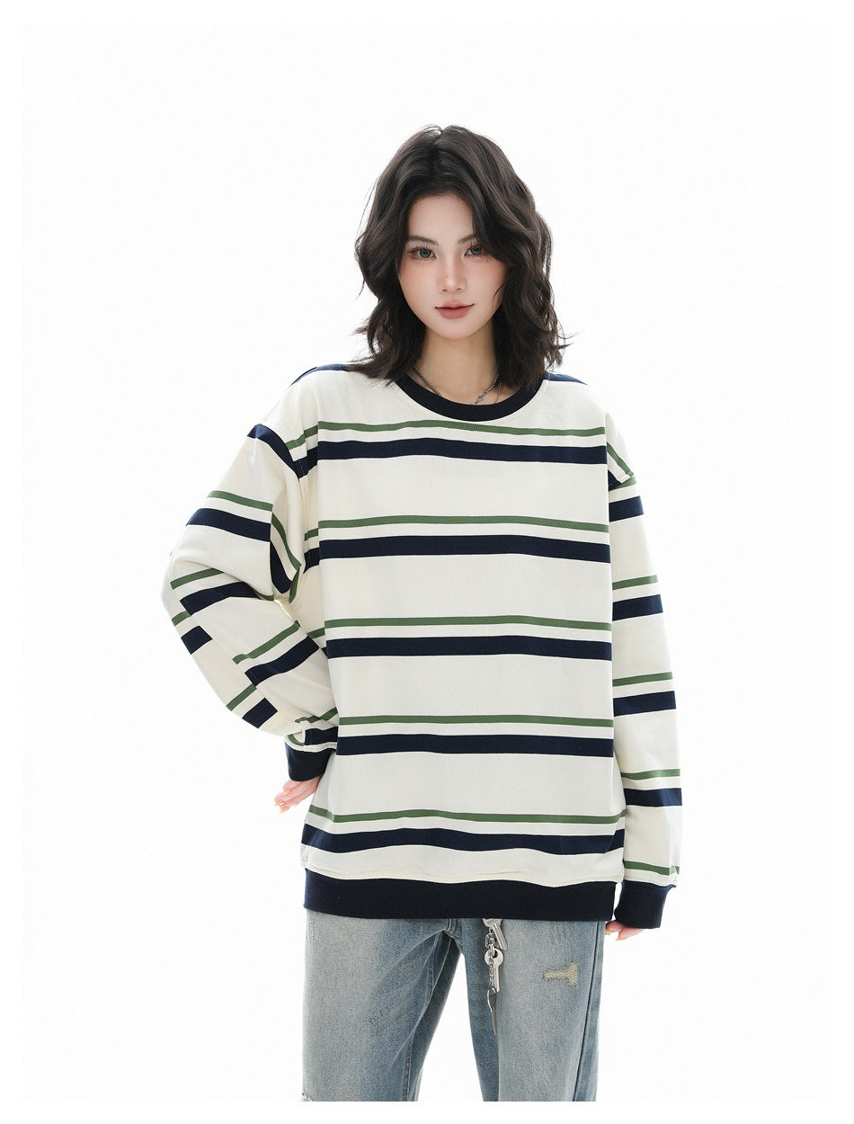 Model in a relaxed cream striped crew-neck sweatshirt with navy and green stripes, one hand on hip, worn with jeans