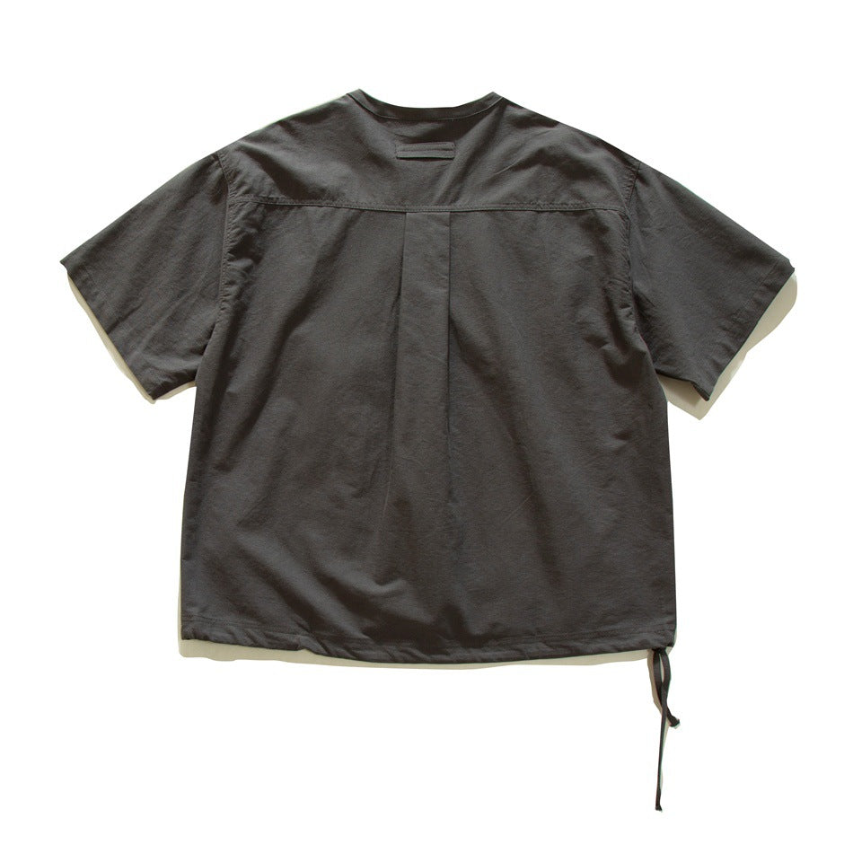 Back view of dark gray short-sleeve shirt with yoke seam, center pleat, neck tab and drawstring hem tie