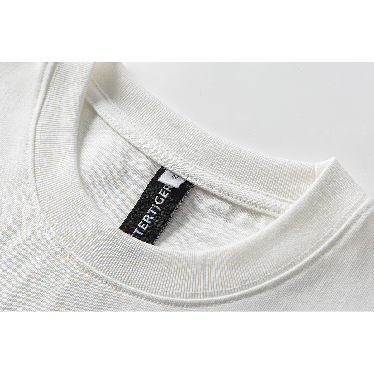 Close-up of a white T-shirt's ribbed crew neckline with a black woven label and size M tag.