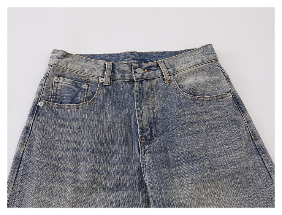 Close-up front view of washed blue-gray jeans showing the button closure and front pockets.