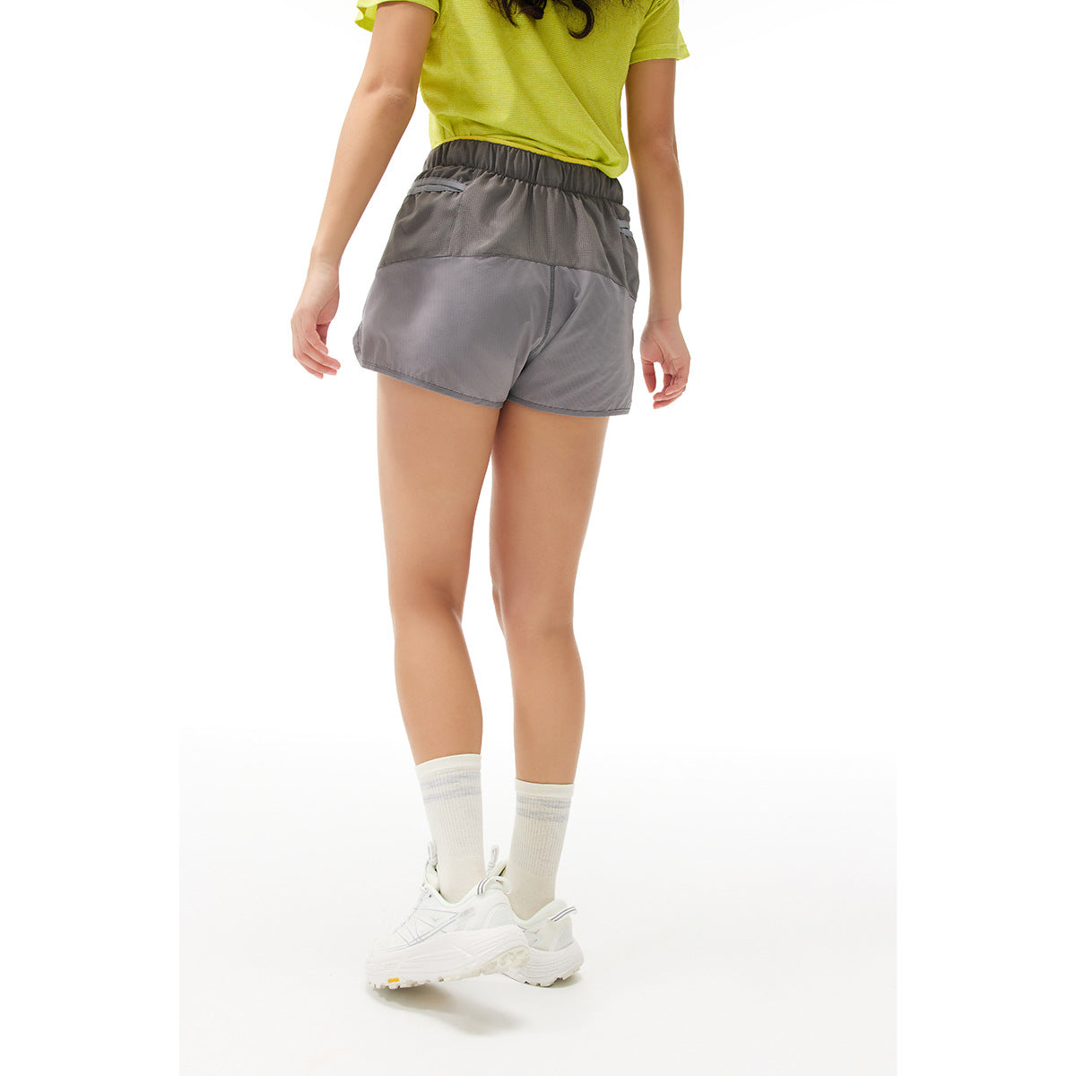 Back view of a model wearing gray running shorts with a darker waistband and color-blocked panels.