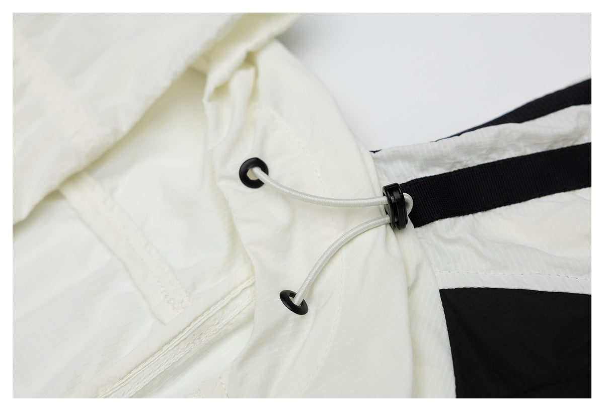 Close-up of a white hooded garment with a gray elastic drawcord, black eyelets and toggle, and black trim.