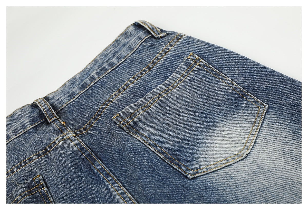 Close-up of a back pocket, belt loops, and faded blue denim with golden stitching.