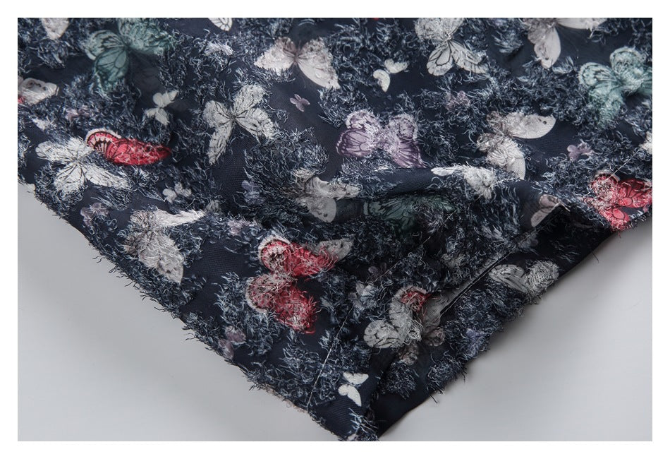 Close-up of dark navy fabric with colorful butterfly prints and a fuzzy, raised texture along a folded edge.