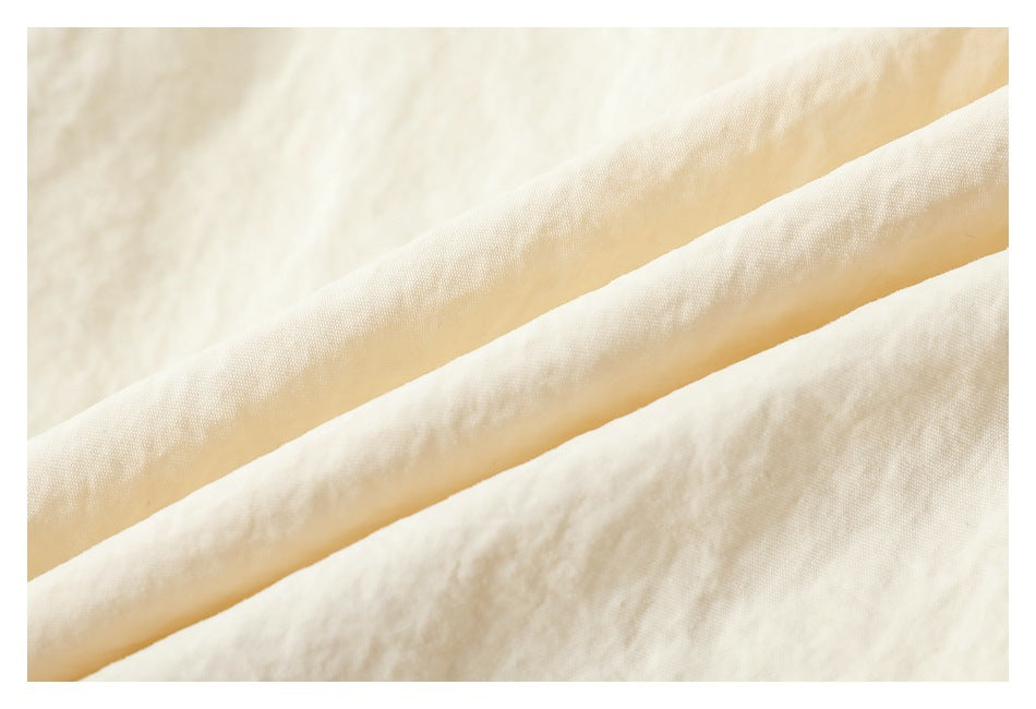 Close-up of cream fabric folded into diagonal ridges, showing its surface texture.