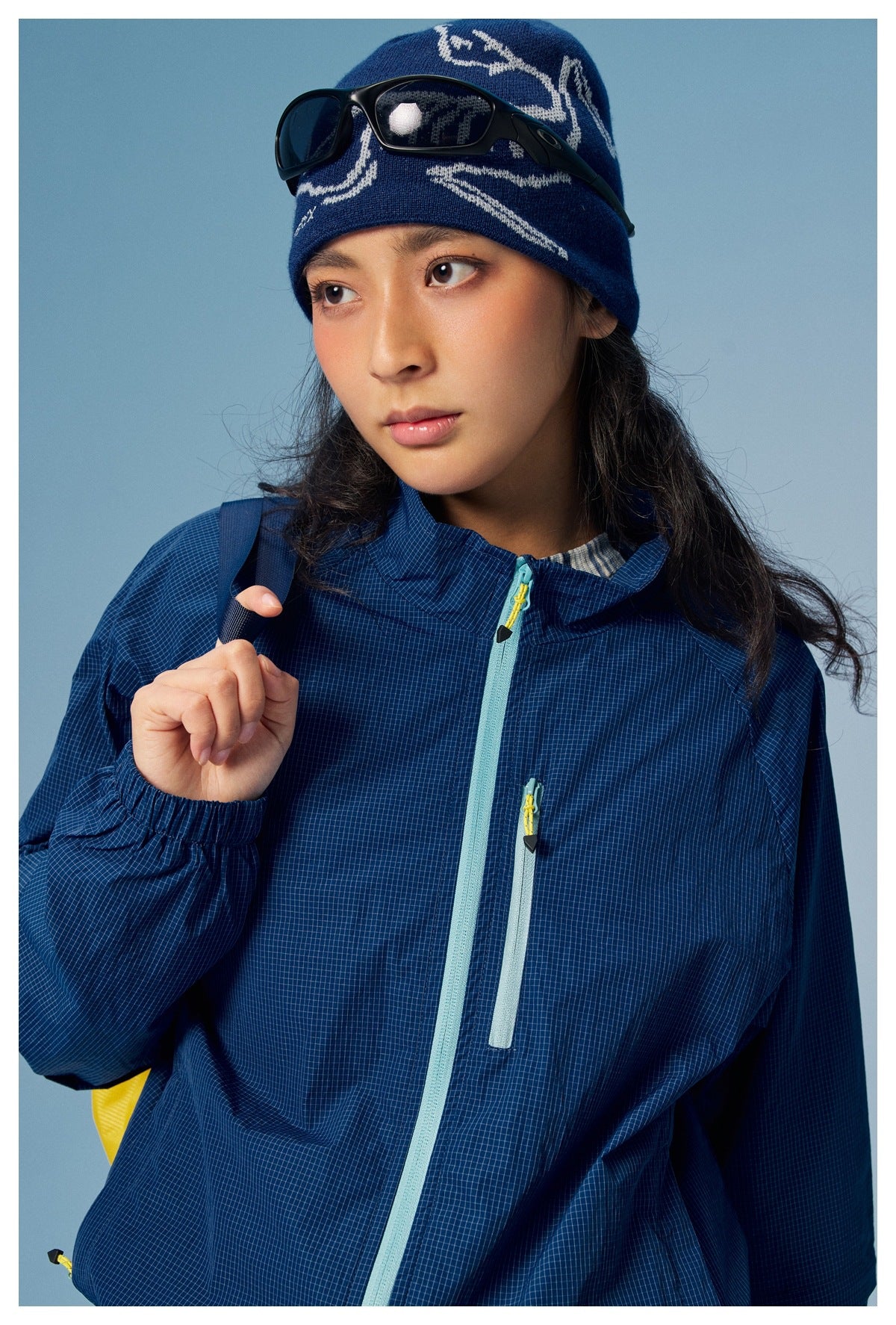 Close-up of a navy grid-pattern jacket with pale blue front and chest-pocket zippers, worn by a model.
