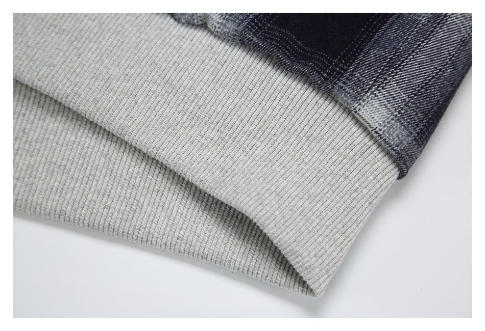 Close-up of a wide light gray ribbed hem on a black, gray, and white plaid garment.