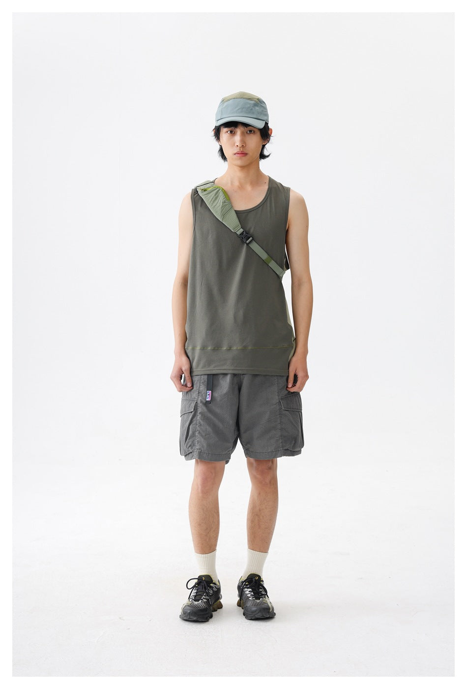Front view of a model wearing a gray-olive sleeveless tank with contrast side panels and gray cargo shorts.