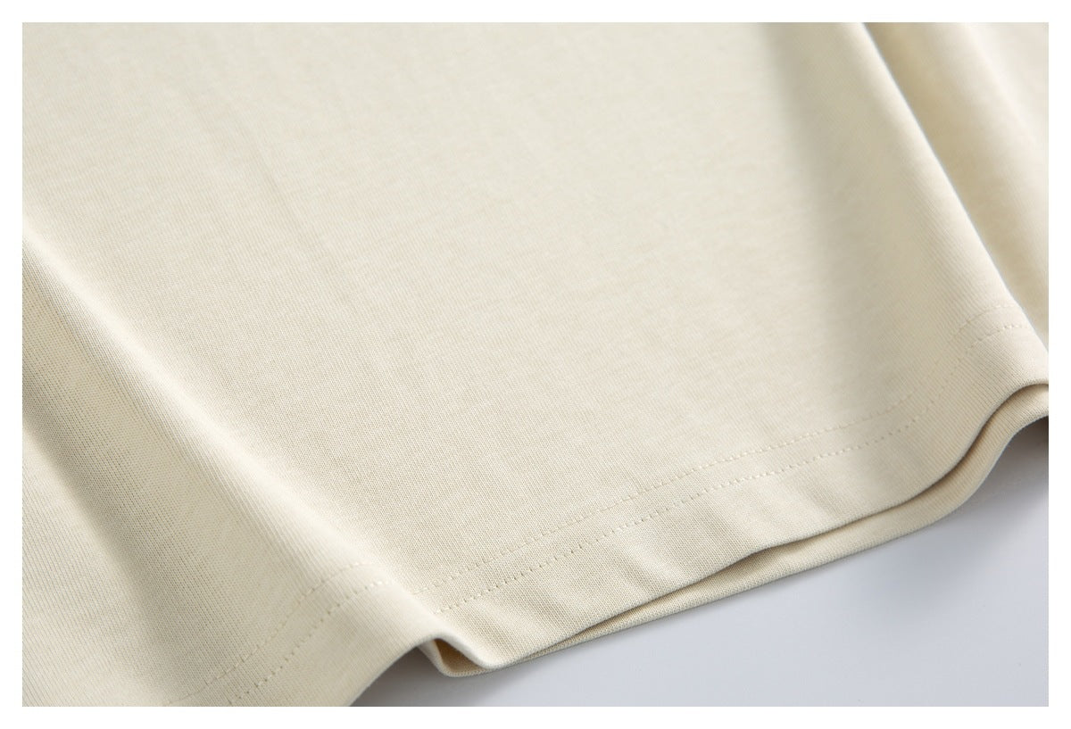Close-up of the plain ivory shirt fabric and double-stitched bottom hem.
