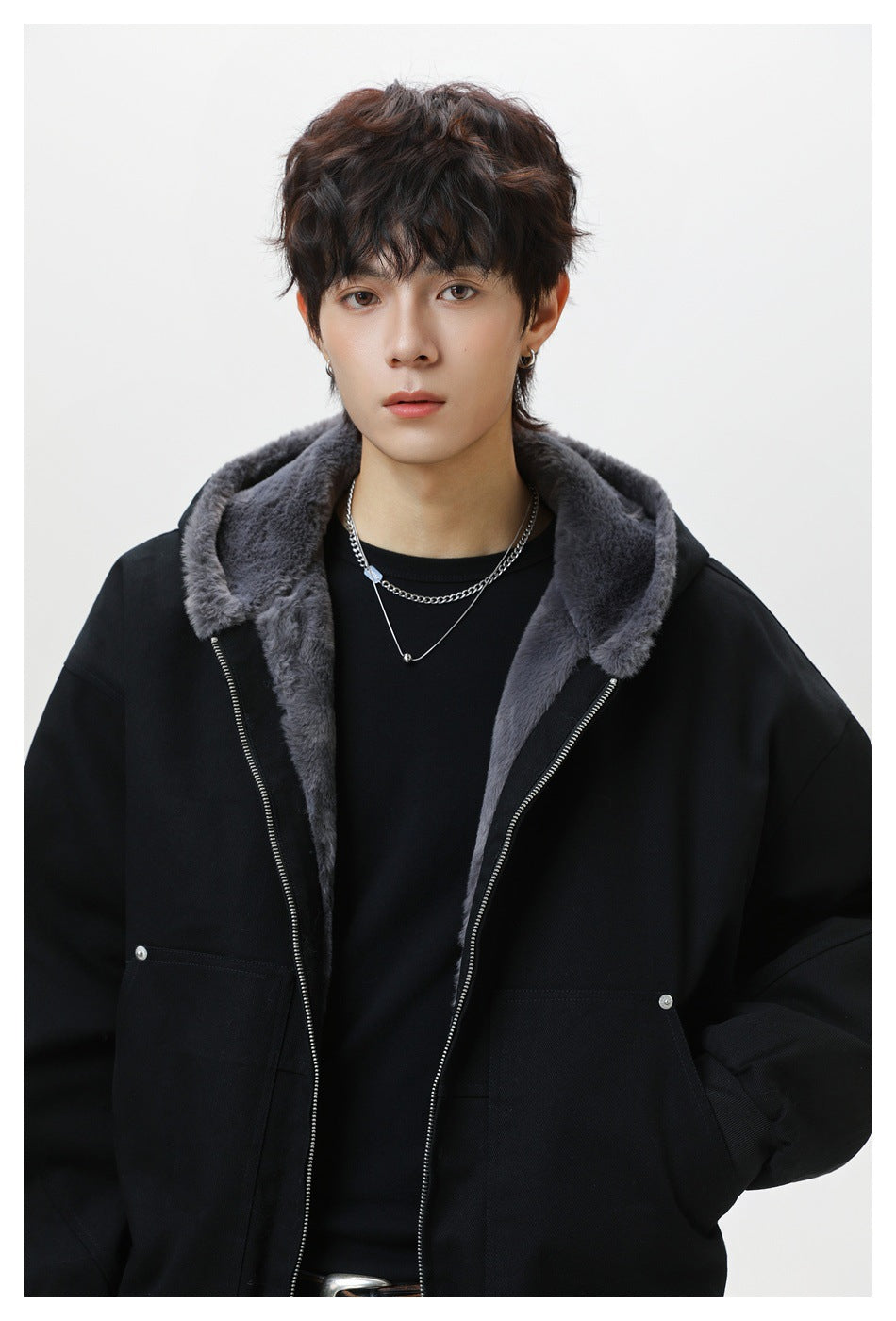 Close view of a model wearing a black jacket with a gray plush-lined hood and silver front zipper.