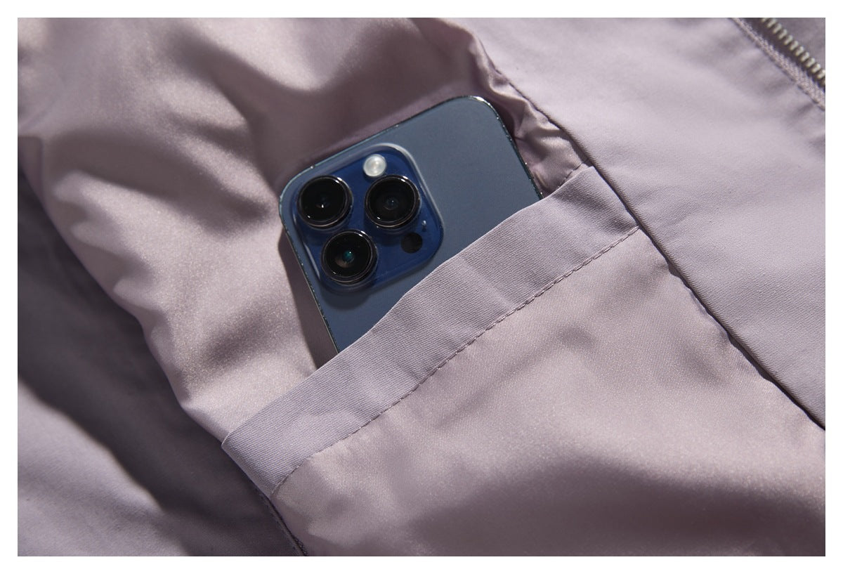 A smartphone tucked into a stitched pocket on a lavender-gray garment.