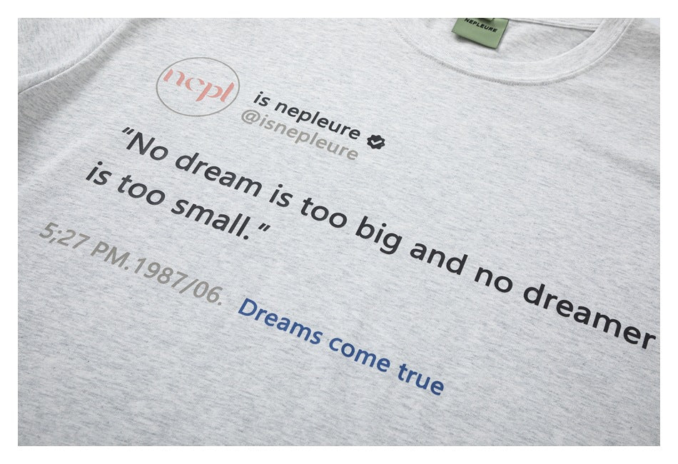 Close-up of a light gray heather T-shirt with a printed English quote and social handle.