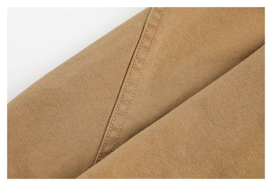 Close-up of folded camel-brown garment fabric with a diagonal stitched seam.