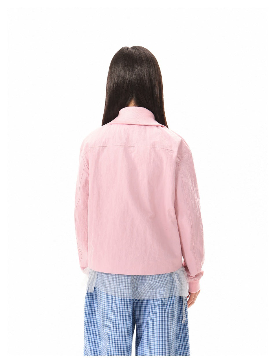 Rear view of a model wearing a pale pink collared jacket with blue checked trousers.