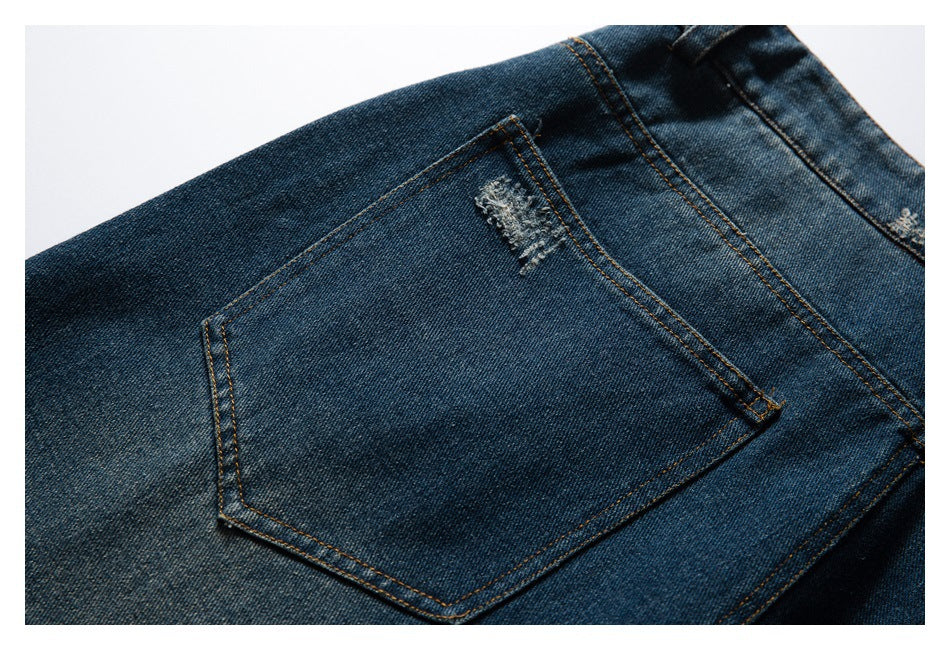 Close-up of a dark blue denim back pocket with contrast stitching and a small distressed patch.