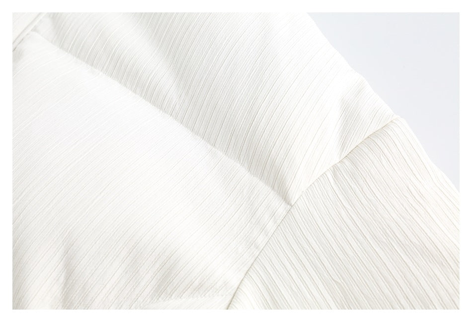 Close-up of an ivory quilted jacket showing its raised linear texture and stitched panel seams.