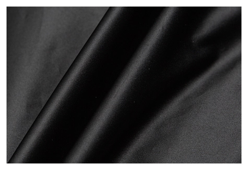 Extreme close-up of smooth black garment fabric with a folded edge.
