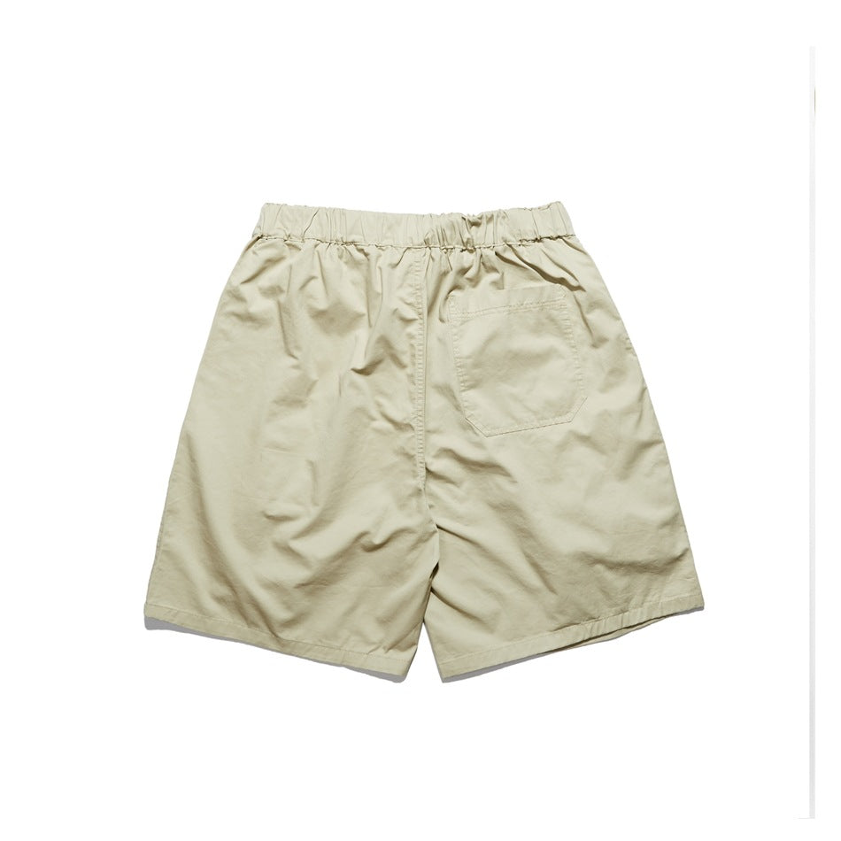 Back view of beige shorts with elastic waistband and a single patch pocket on a white background