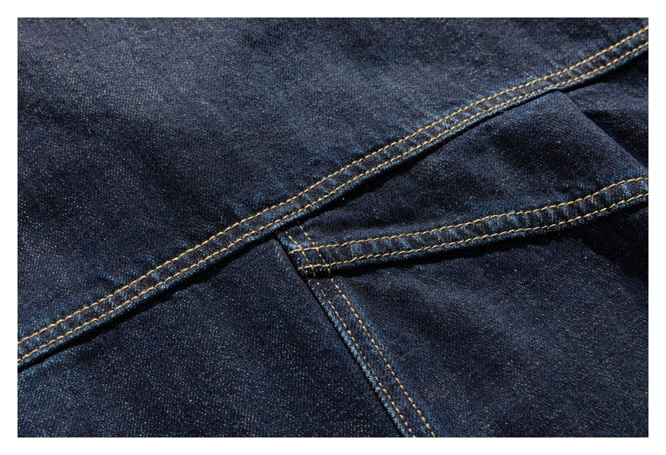 Close-up of intersecting seams and golden stitching on dark indigo denim.
