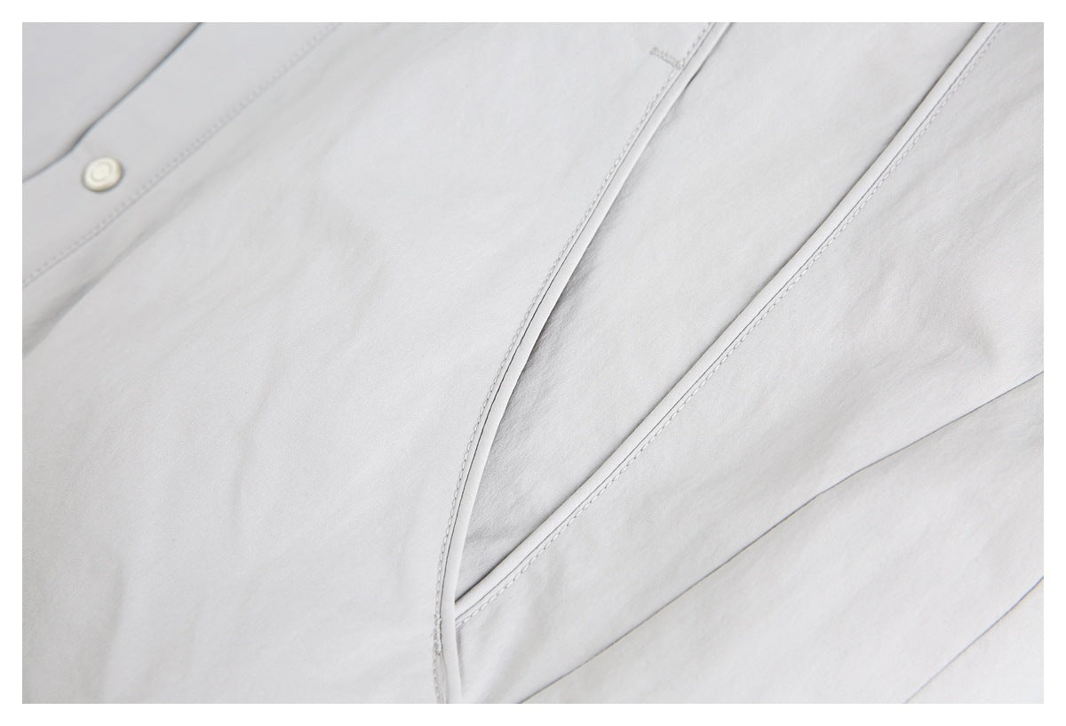 Close-up of the light gray jacket's front seam panels and a round snap.