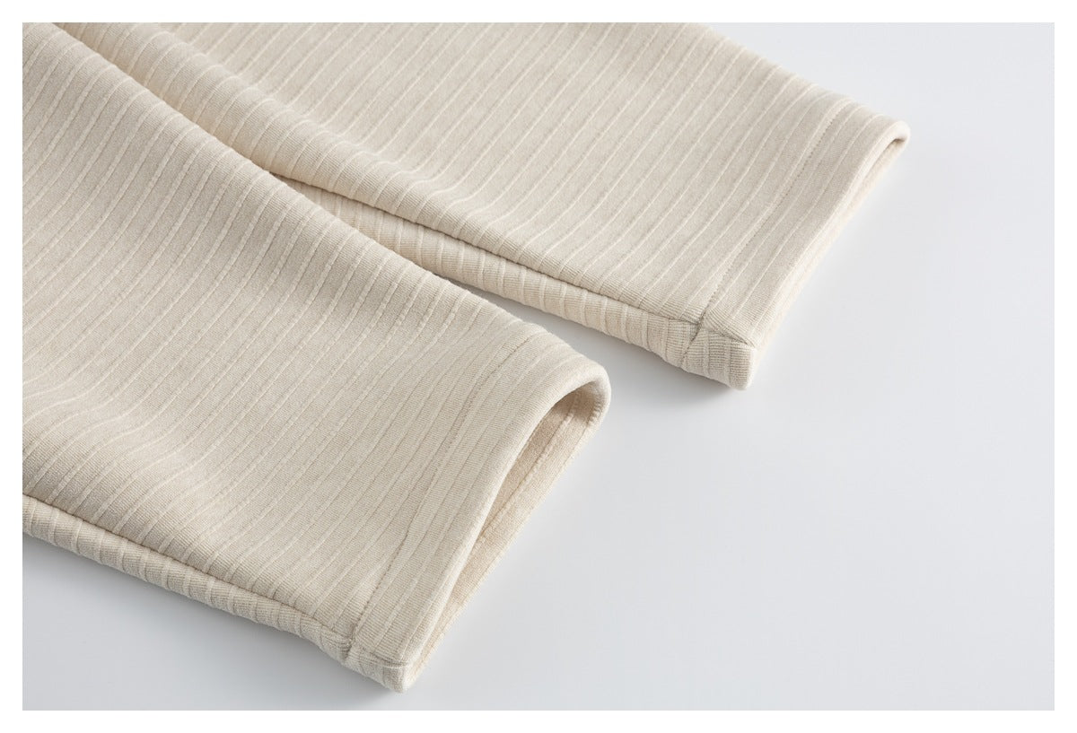 Close-up of the cream ribbed knit sleeve cuffs, showing their folded edges and stitching.