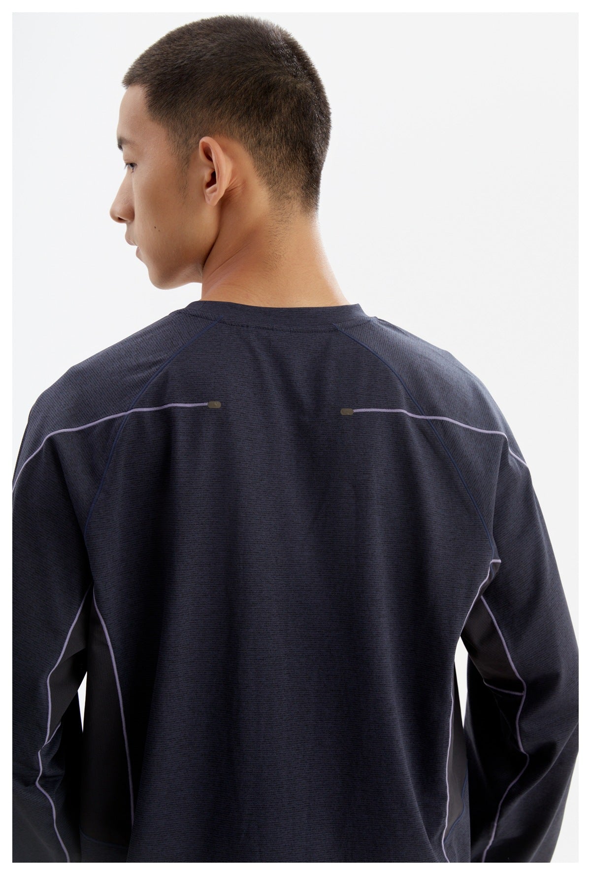 Back view of a model wearing a dark navy long-sleeve top with lilac piping and shoulder accents.