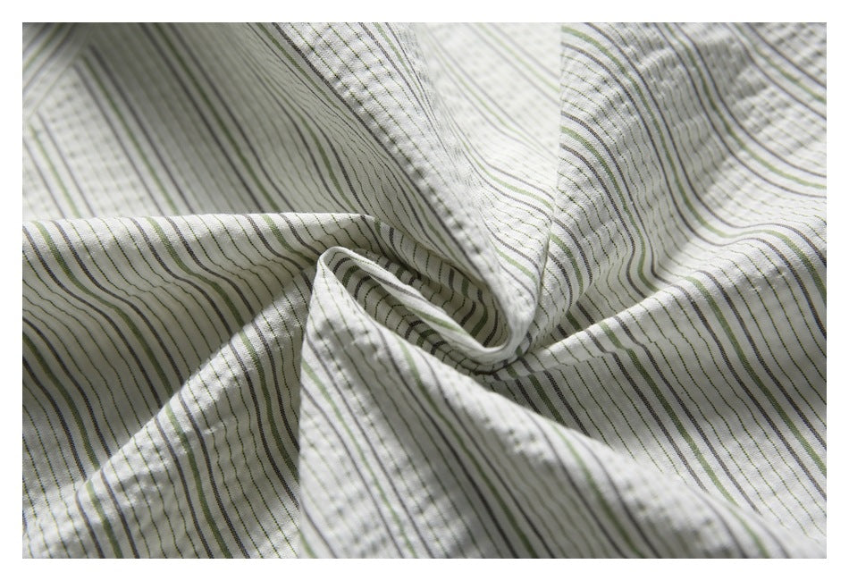 Close-up of the white shirt fabric, showing narrow green and gray stripes and a textured woven pattern.