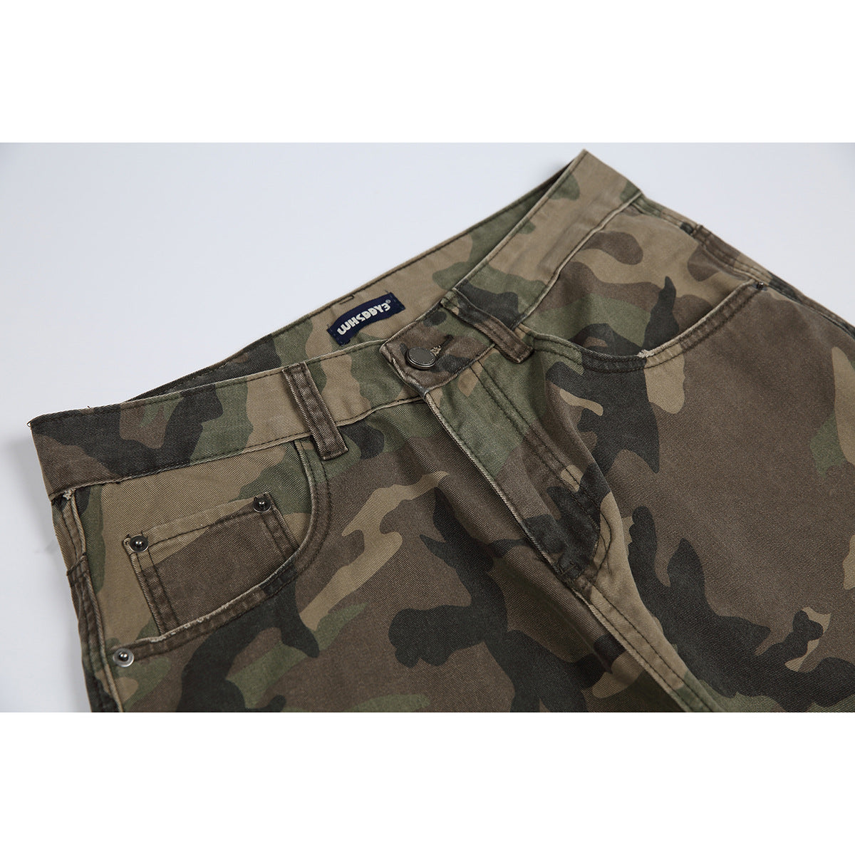 Close-up of the front waist and pocket of olive, brown and black camouflage trousers.