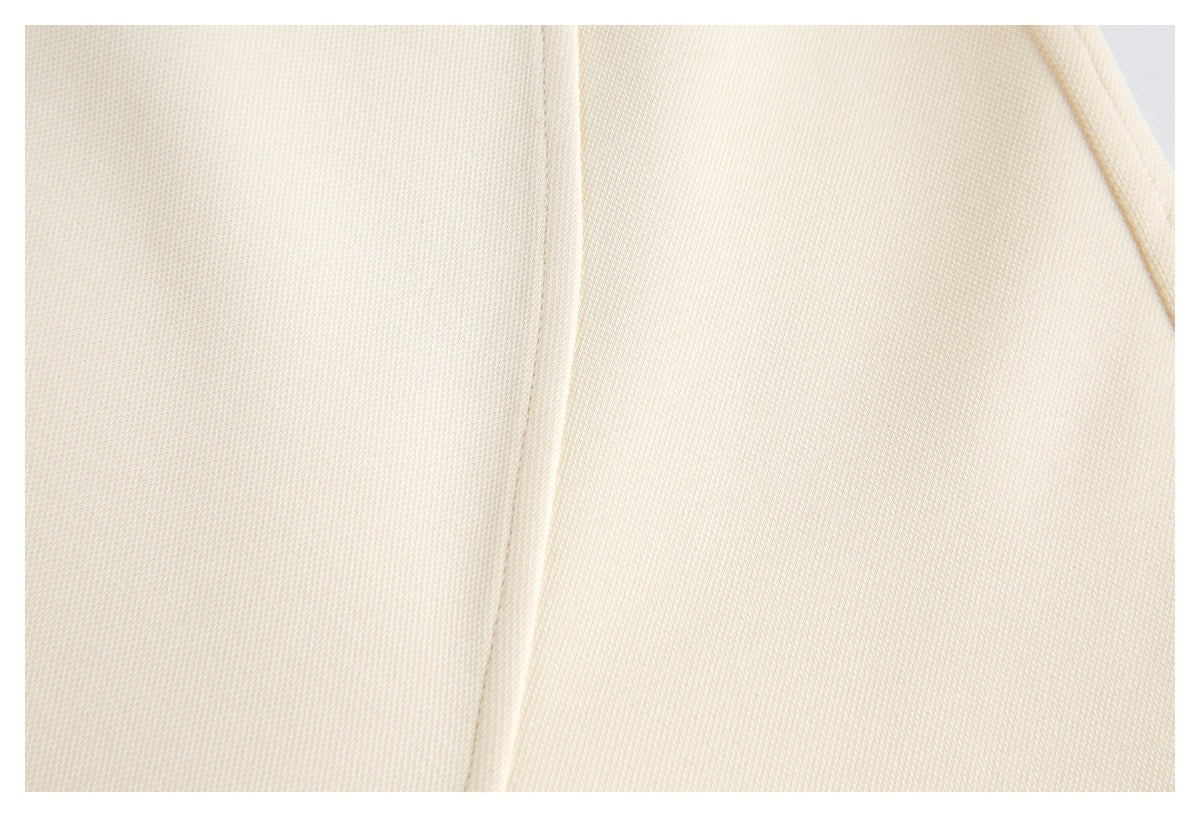 Extreme close-up of cream-colored garment fabric and a stitched seam.