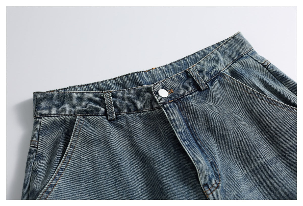 Cropped front view of washed blue jeans showing the waistband, button, fly, belt loops, and pocket opening.