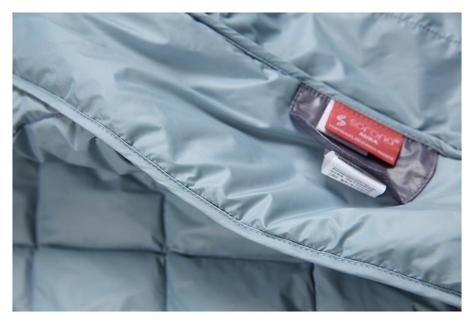 Close-up of the light blue-gray quilted garment's inner lining and sewn-in neck labels.