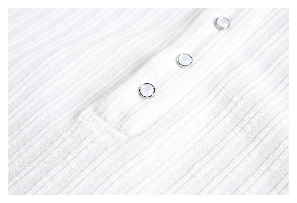 Close-up of three snap buttons on the placket of a white ribbed shirt.