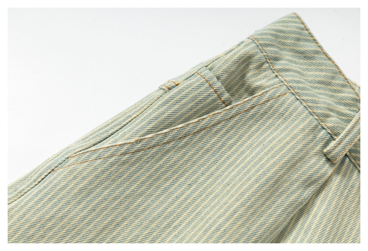 Close-up of pale blue and cream striped denim with a belt loop and contrast stitching.