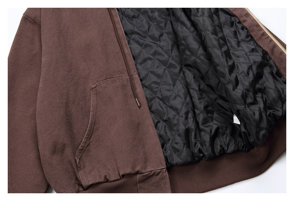 Close-up of a brown zip hoodie opened to show its black quilted lining, front pocket, zipper, and ribbed hem.