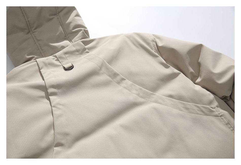 Close-up of a beige jacket panel with a stitched strap and small metal D-ring.