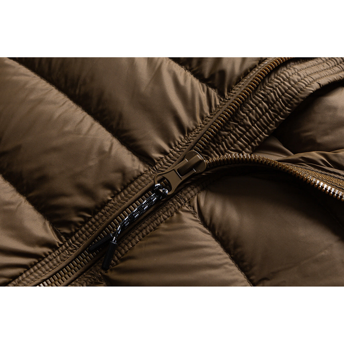 Close-up of the brown quilted jacket's zipper, teeth, and pull tab.