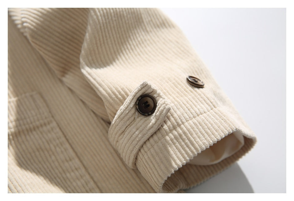 Close-up of a cream ribbed jacket sleeve cuff with a dark button and adjustable tab.