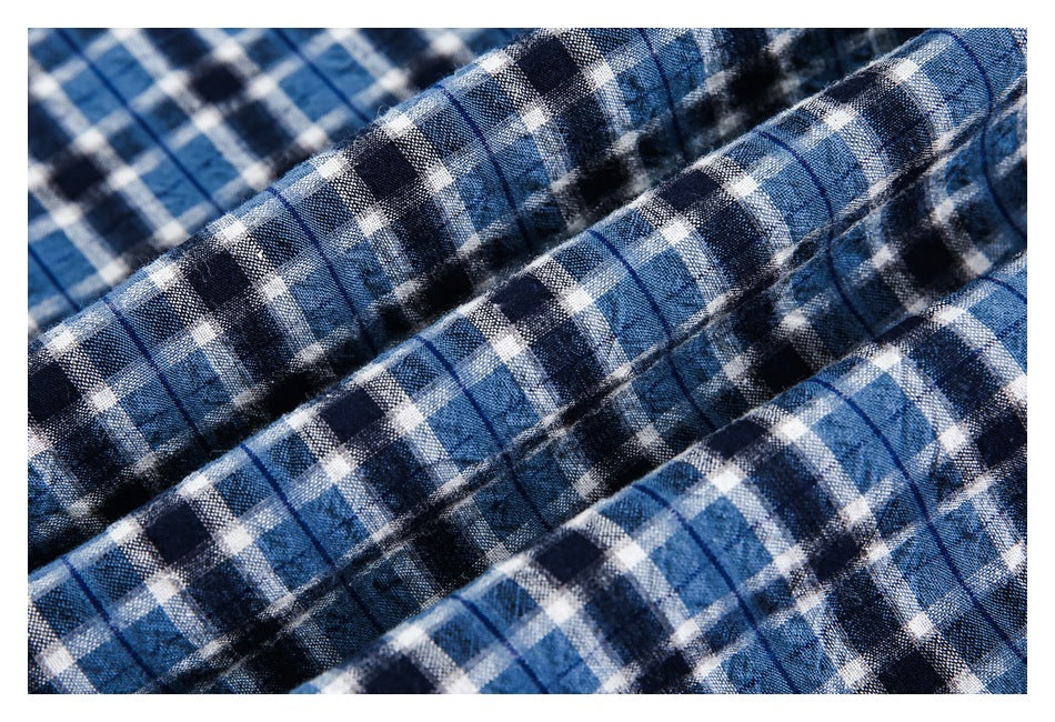 Macro view of the blue, navy and white plaid shirt fabric gathered into folds.